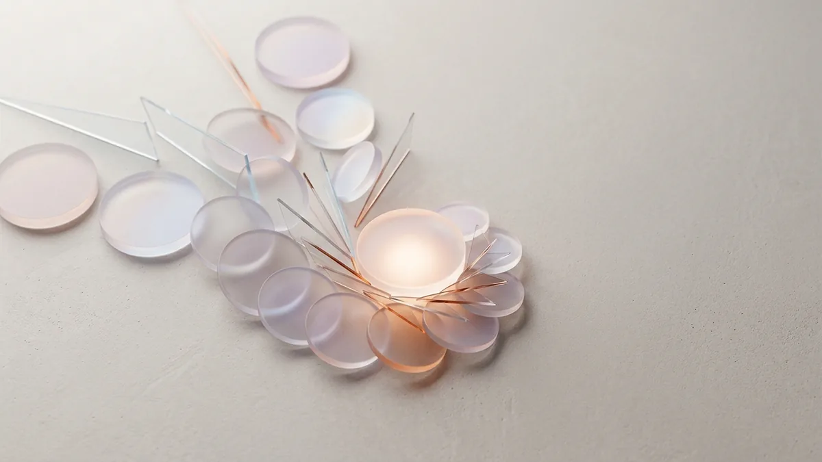 Clear glass discs linked to a glowing centre by thin lines on a light surface